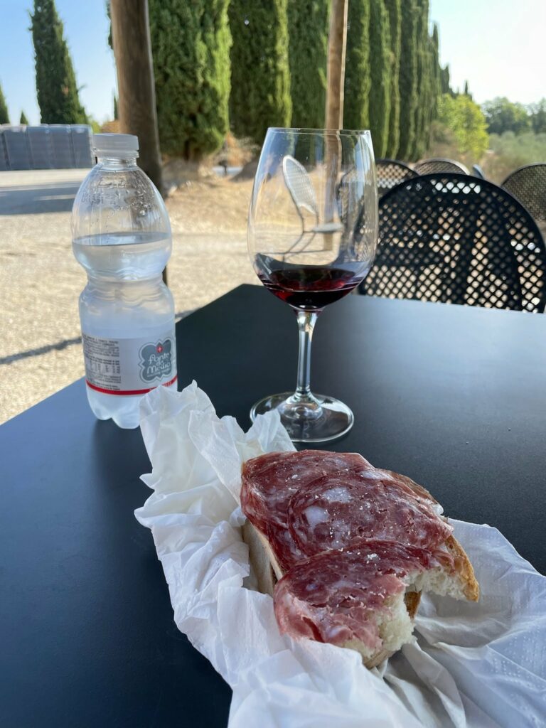 Salami and bread with wine and a water bottle. 
